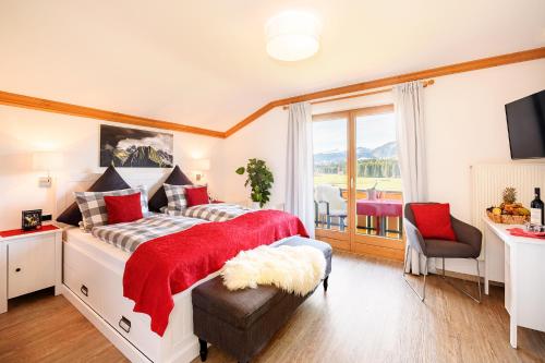 奥伯斯特多夫"Haus Berktold" - Annehmlichkeiten von 4-Sterne Familien-und Wellnesshotel Viktoria können mitbenutzt werden的一间卧室配有一张带红色毯子的大床