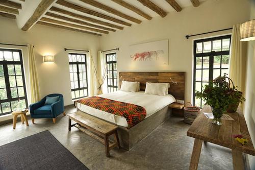 育空河Arusha Villa Karamu Coffee Estate的一间卧室配有一张大床和一张蓝色椅子