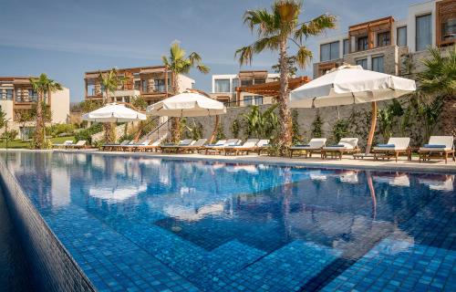 亚力卡瓦克Allium Bodrum Resort & Spa的一个带遮阳伞和躺椅的大型游泳池
