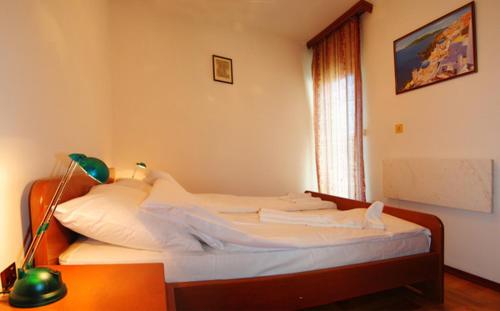 弗尔尼亚奇卡矿泉镇Apartman Lili的一间卧室配有一张带白色床单和一盏灯的床。