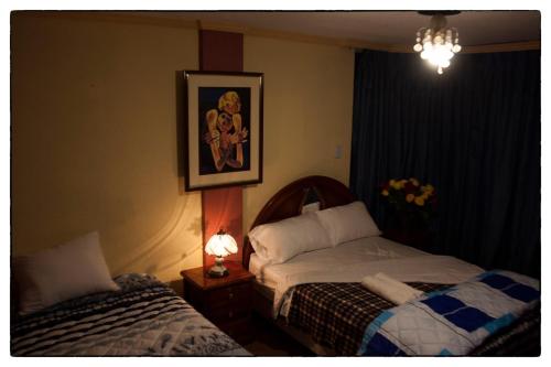 SangolquíSueños del Valle的卧室配有两张床,墙上挂着一幅画