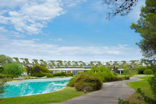卡斯特拉巴特滨海Ethra Reserve Kalidria的一座公园内的游泳池,其建筑背景