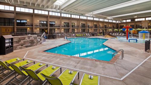 布卢明顿美国卢明顿购物中心贝斯特韦斯特酒店的一座大游泳池,位于大楼前方,配有椅子