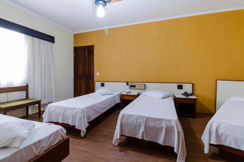 南圣卡埃塔诺Hotel Acacia的一间设有两张床和黄色墙壁的客房