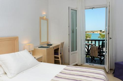 纳乌萨卡勒普叟酒店的一间带一张床和一张书桌的卧室以及一个阳台