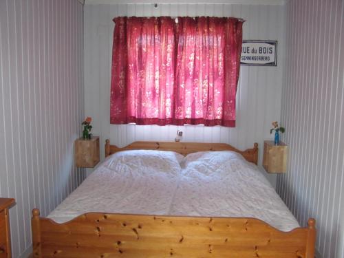 赫尔辛厄提丝维尔德艮班德布住宿加早餐旅馆的一间卧室配有一张木床和粉红色的窗户