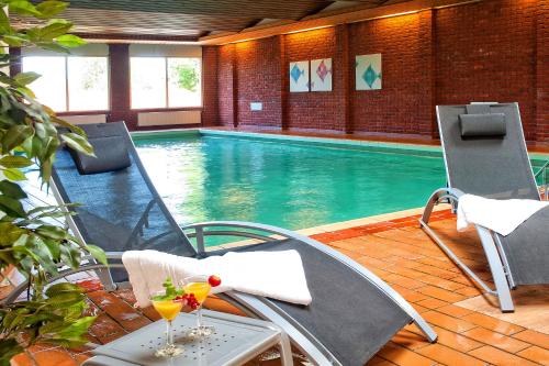 洛赫姆Hotel Hof van Gelre by Flow的游泳池配有两把椅子和一张桌子,并提供饮料