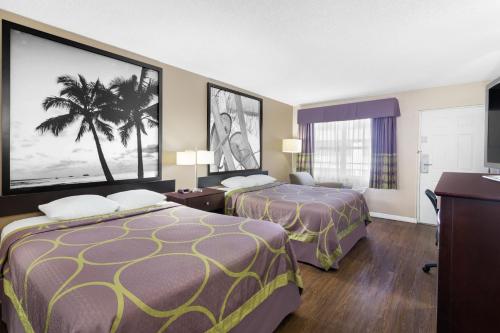 埃伦顿速8 - 埃伦顿汽车旅馆的酒店客房设有两张床,墙上挂着一棵棕榈树。