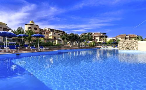 马里内拉Colonna Beach Hotel Marinella的一个带蓝色椅子和遮阳伞的大型游泳池