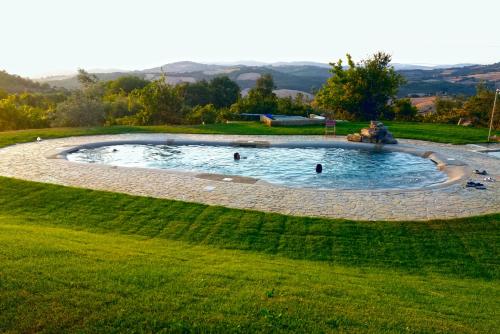 拉迪孔多利Agriturismo Le Canterie的草地上的一个圆形游泳池,里面的人