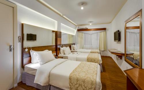 瓜拉普阿瓦Kuster Hotel的酒店客房设有两张床和电视。
