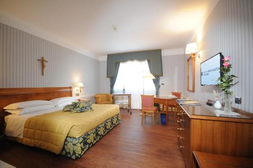 圣乔瓦尼·罗通多Hotel Centro di Spiritualità Padre Pio的配有一张床和一张书桌的酒店客房