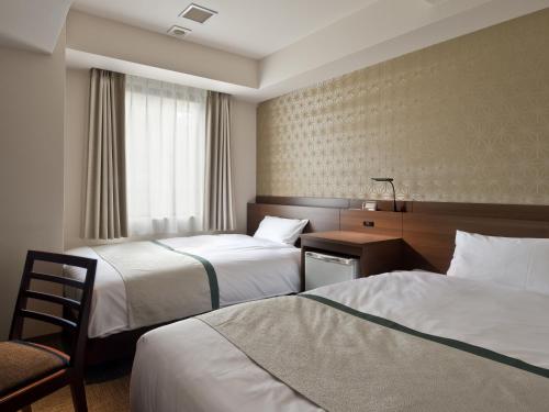 东京神田可可尼东正经济型酒店的酒店客房配有两张床和一张桌子及椅子
