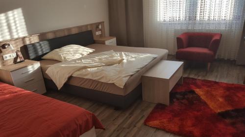 KlingenbachFerienhaus Karall的一间卧室配有一张床和一张红色椅子