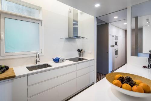 巴塞罗那花园景人居公寓的厨房配有白色橱柜和一碗水果