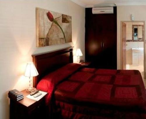 勒斯滕堡勒斯滕堡精品酒店的一间卧室配有红色的床和一张带台灯的桌子