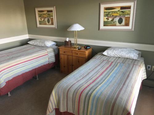 萨斯卡通劳拉小屋宾馆的客房设有两张床和一张带台灯的桌子。