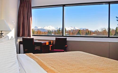 安克雷奇亚历克斯套房酒店的酒店客房设有一张床、一张书桌和一个大窗户。