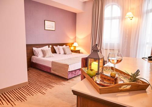 索非亚索非亚狮子酒店的酒店客房带一张床和一杯葡萄酒