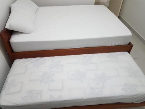 乌巴图巴Apartamento Avenida Wilson的小客房内的两张床,配有白色床单