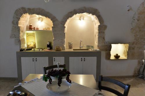 阿尔贝罗贝洛Trullo Assenzio的厨房设有两个拱门,桌子上有一个花瓶