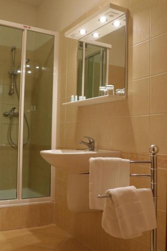 新扎姆基Hotel Grand的一间带水槽、淋浴和镜子的浴室
