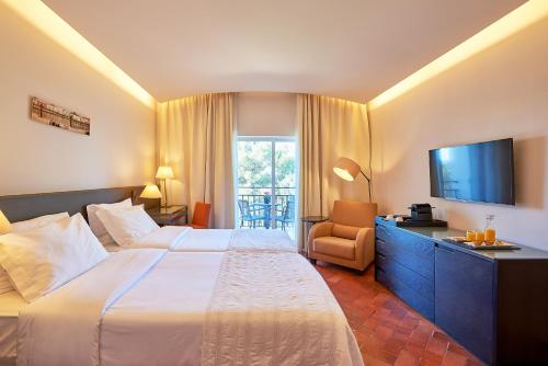 波尔蒂芒佩尼娜高尔夫度假酒店的酒店客房设有一张大床和一台电视。