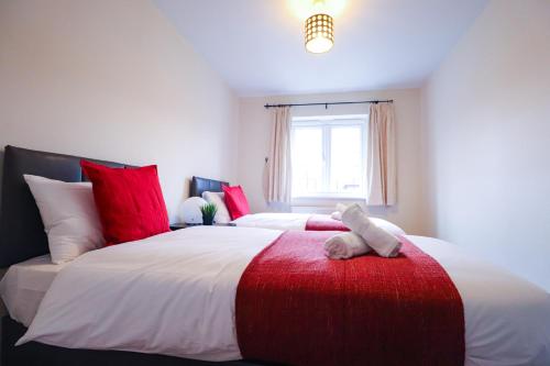 威森肖Royal Oak Home的一间卧室配有两张带红白色枕头的床