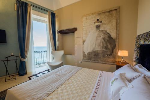 锡拉库扎奥提加皇家套房酒店的一间卧室配有一张床,窗户墙上挂着连衣裙