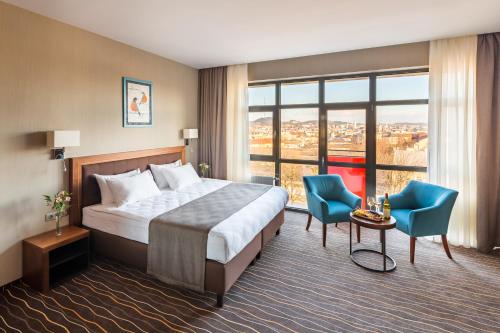 利沃夫金牛座城市酒店的酒店客房,配有一张床和两张蓝色椅子