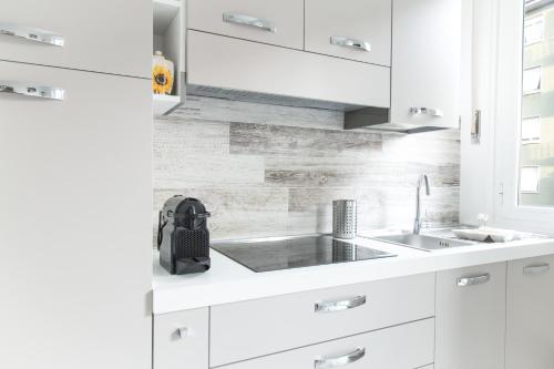 米兰Mi Suzzani的厨房配有白色橱柜和水槽