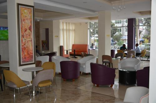 亚的斯亚贝巴阿兹曼酒店的一间设有桌椅的餐厅,以及坐在桌子上的人