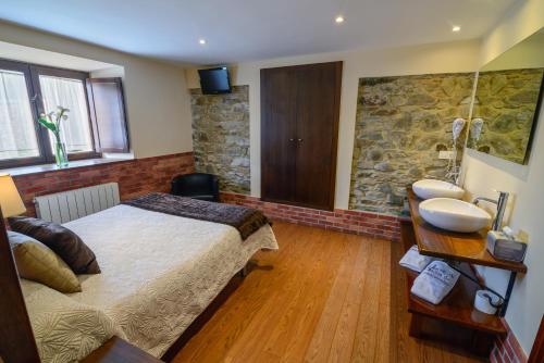 Oviñana卡松纳德亚诺罗佐乡村公寓的一间卧室设有一张大床和石墙