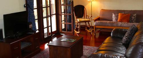 曼吉马普三叶草小屋乡村度假酒店的带沙发和电视的客厅