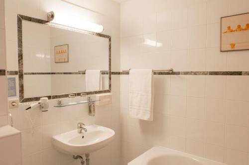 莱比锡勒佩兹家尔航德酒店的白色的浴室设有水槽和镜子