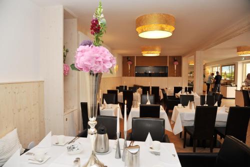 吕本瑙安拉格斯塔里克酒店的一间设有白色桌椅的餐厅,并种植了粉红色的鲜花