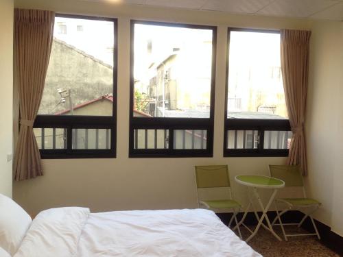 台南开山民宿 的卧室设有窗户、一张床和一张桌子及椅子