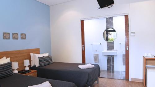 布鲁姆布鲁姆海滩旅舍的一间带两张床的卧室和一间带镜子的浴室