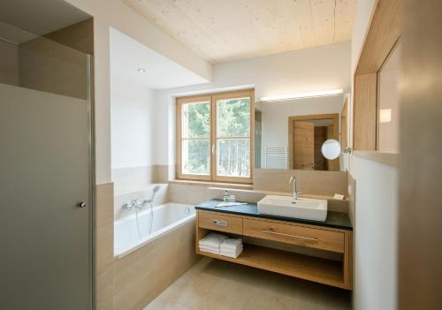 HeilbrunnNaturhotel Bauernhofer的浴室配有盥洗盆和浴缸。