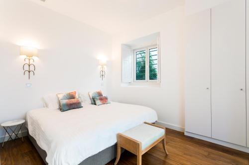 埃斯托利尔Chalet Estoril Luxury Apartments的白色的卧室设有白色的床和窗户。