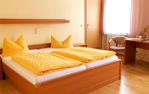 NachterstedtHotel zum Schwan的一间卧室配有一张带黄床单的床和一张书桌。
