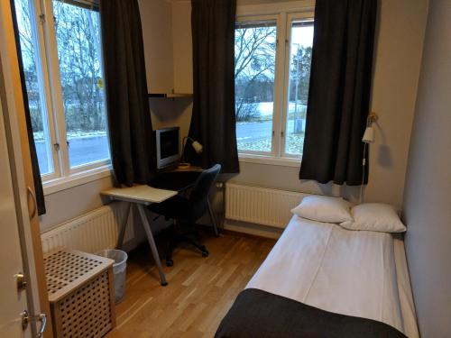 韦斯特罗斯Hotell Hässlö的客房设有两张床、一张书桌和窗户。