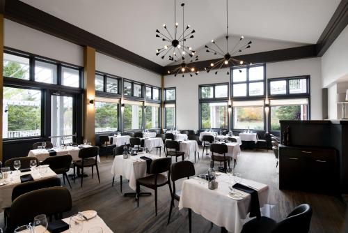 梅戈格德斯萨布勒斯高尔夫庄园酒店的餐厅设有白色的桌椅和窗户。