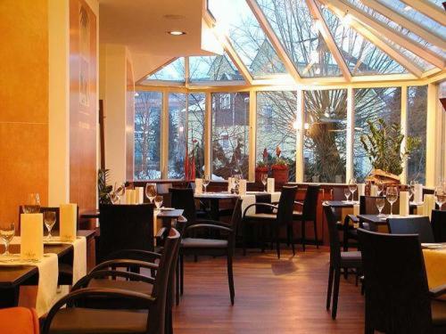 梅舍德冯·科尔夫的休息及休闲酒店的餐厅设有桌椅和大窗户。