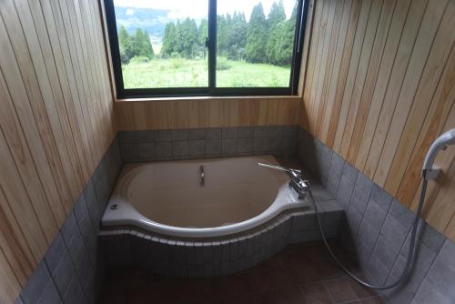 南阿苏村瓦卡旅馆的带浴缸的浴室和窗户