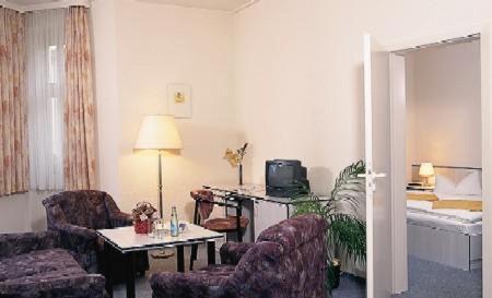德累斯顿库哈斯可切酒店及餐厅的客厅配有椅子、桌子和床