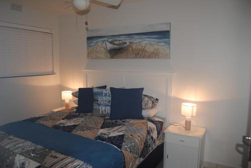 斯科特堡11 Coral Sands的一间卧室配有一张带两盏灯和一幅画的床铺