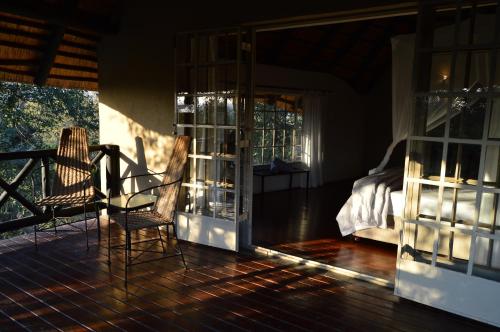 玛洛斯帕克Kruger River Villas - Mtombo的客房设有阳台、一张床和玻璃门
