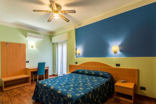 文蒂米利亚卡利普索酒店 的一间卧室配有一张床和吊扇