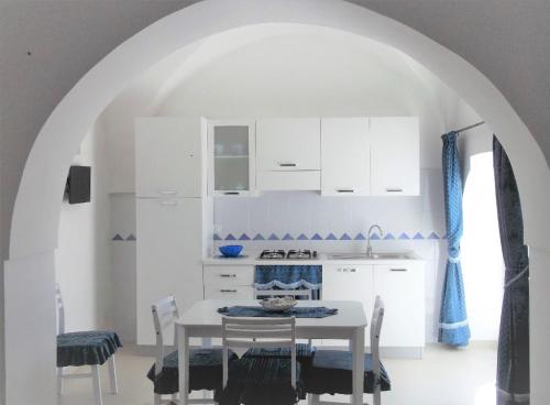 奥斯图尼马塞里亚贝内代迪公寓的厨房配有白色橱柜和桌椅